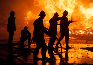 silhouettes of fire fighters fighting a fire