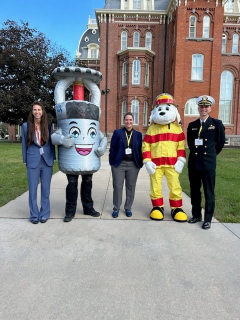 a group of 5 people posing on a path in front of building. Two of the people are wearing mascot costumes.