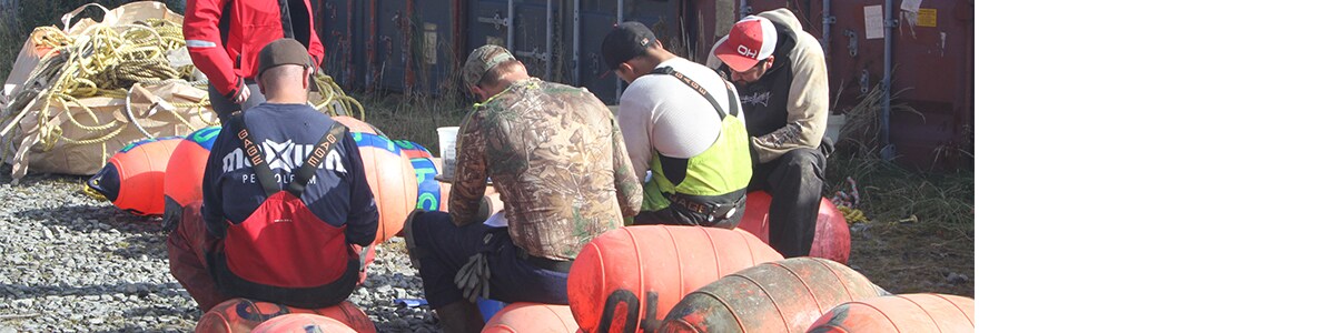 A NIOSH researcher administers a survey to group of crab fishermen at the docks in Dutch Harbor, Alaska.