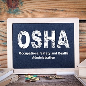 OSHA, Occupational Safety and Health Administration written on a chalkboard sitting on a desk.