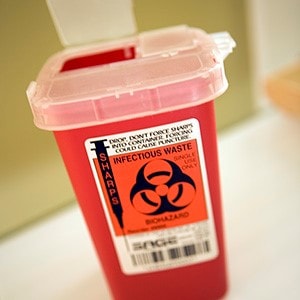 Hospital sharps container with lid open.