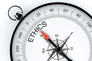 Compass with the dial pointed to the word ethics.