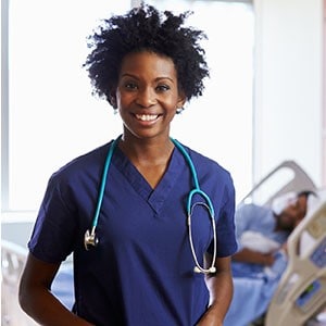 Nurse standing in patient room with patient in the background.