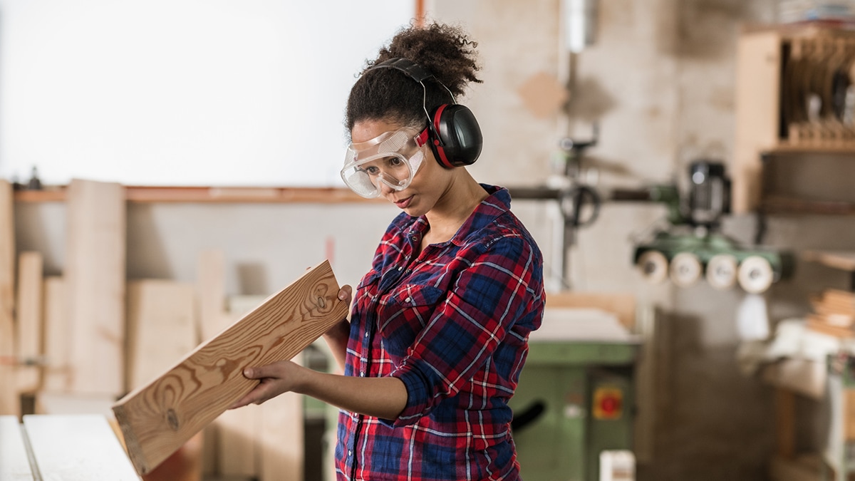 Pregnant woodworker wearing eye and hearing protection.