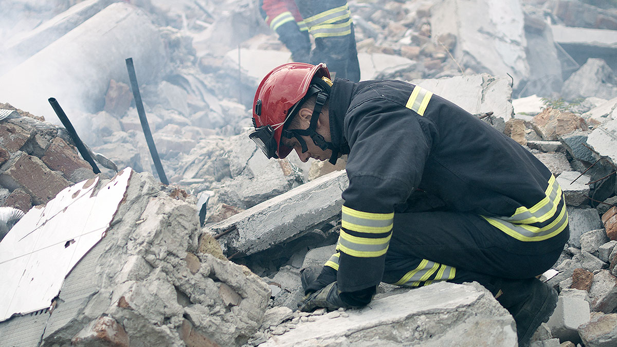 Male rescuers removing concrete rubble