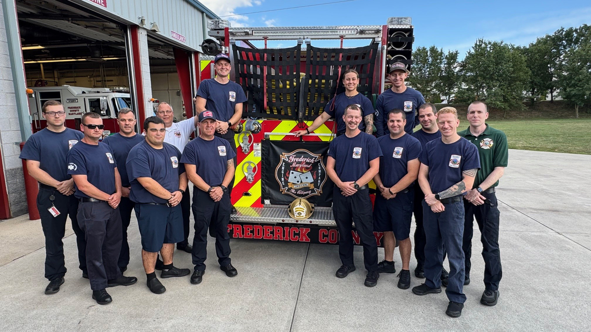 Group of firefighters in front of a truck with a gold helmet in between them