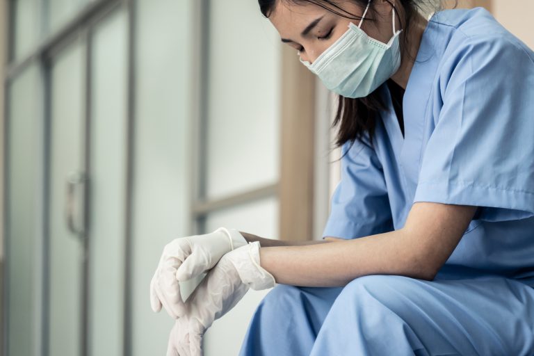 Una trabajadora sanitaria sentada, con aspecto cansado.