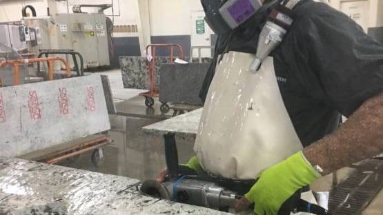 Worker cutting stone countertop using wet method.