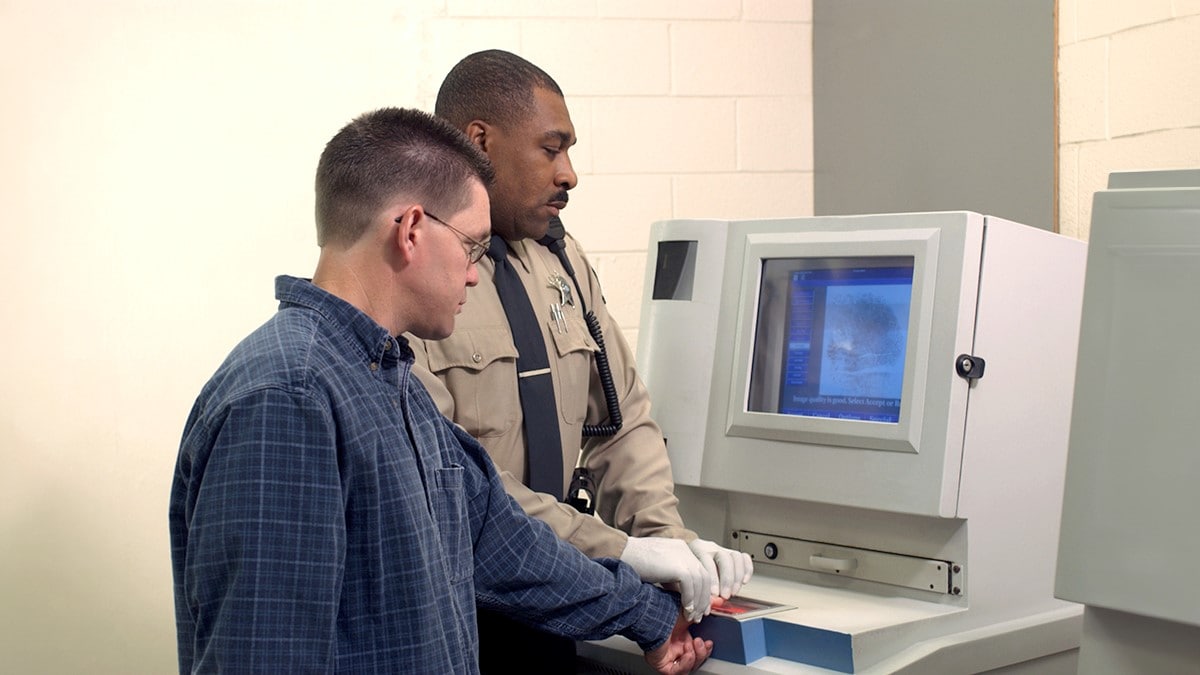 Correctional officer taking fingerprints of a detained person.