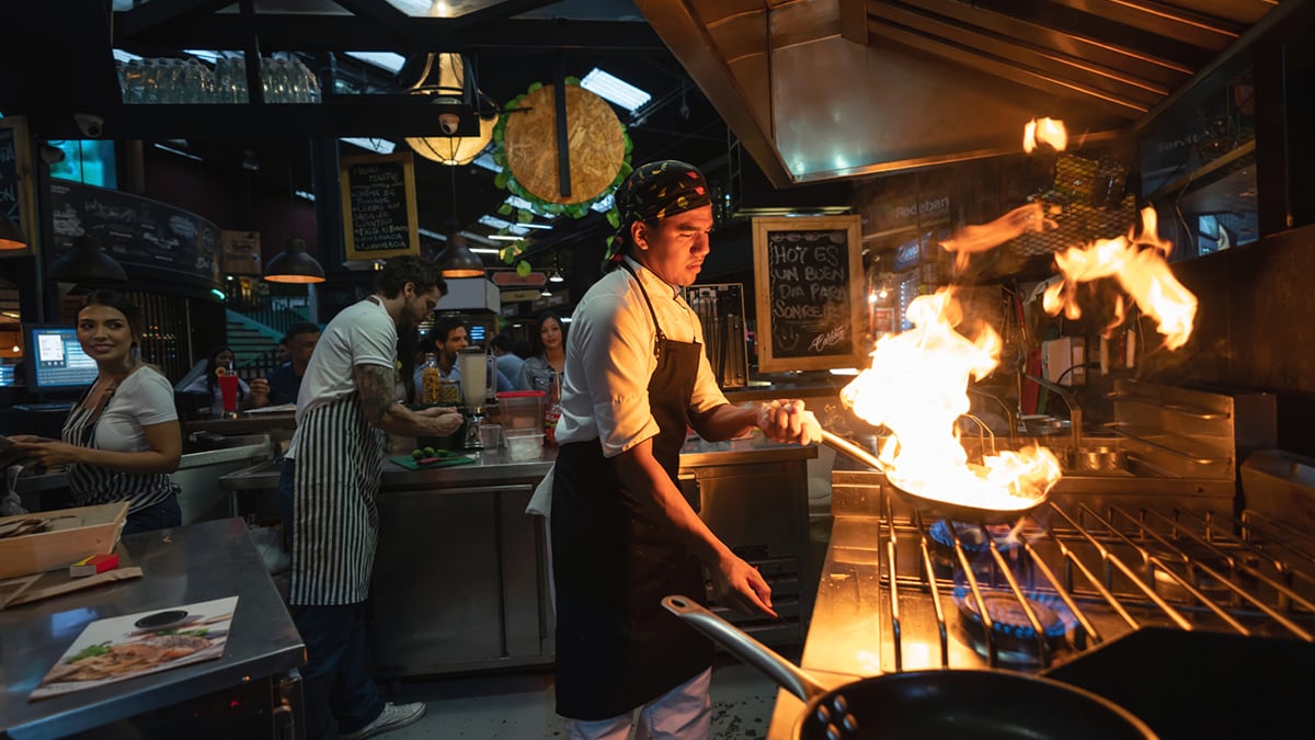 Chef cooking at a restaurant flaming the food - small business concept