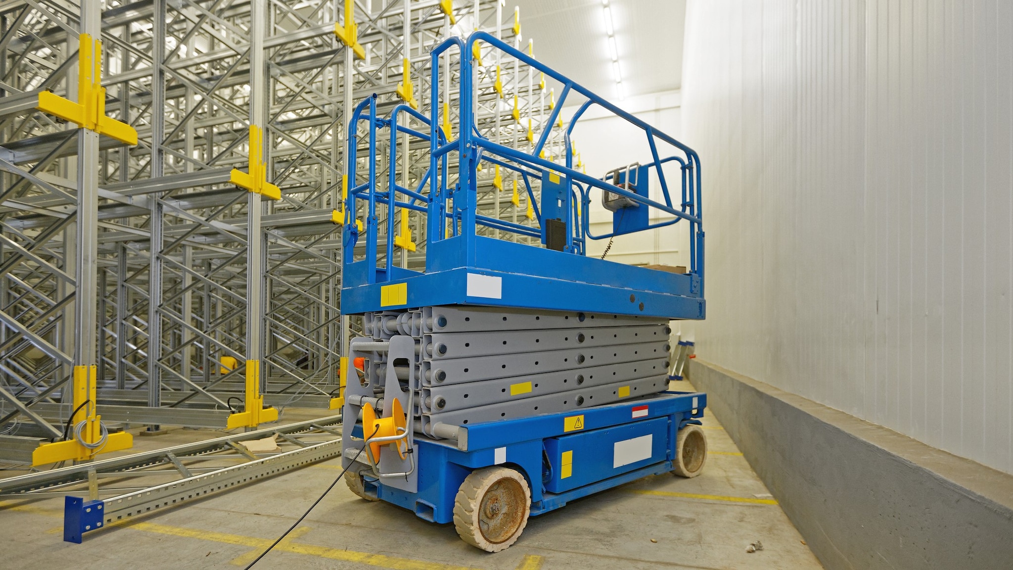 A blue aerial lift is in a warehouse. Photo by Marco Berik/Getty Images