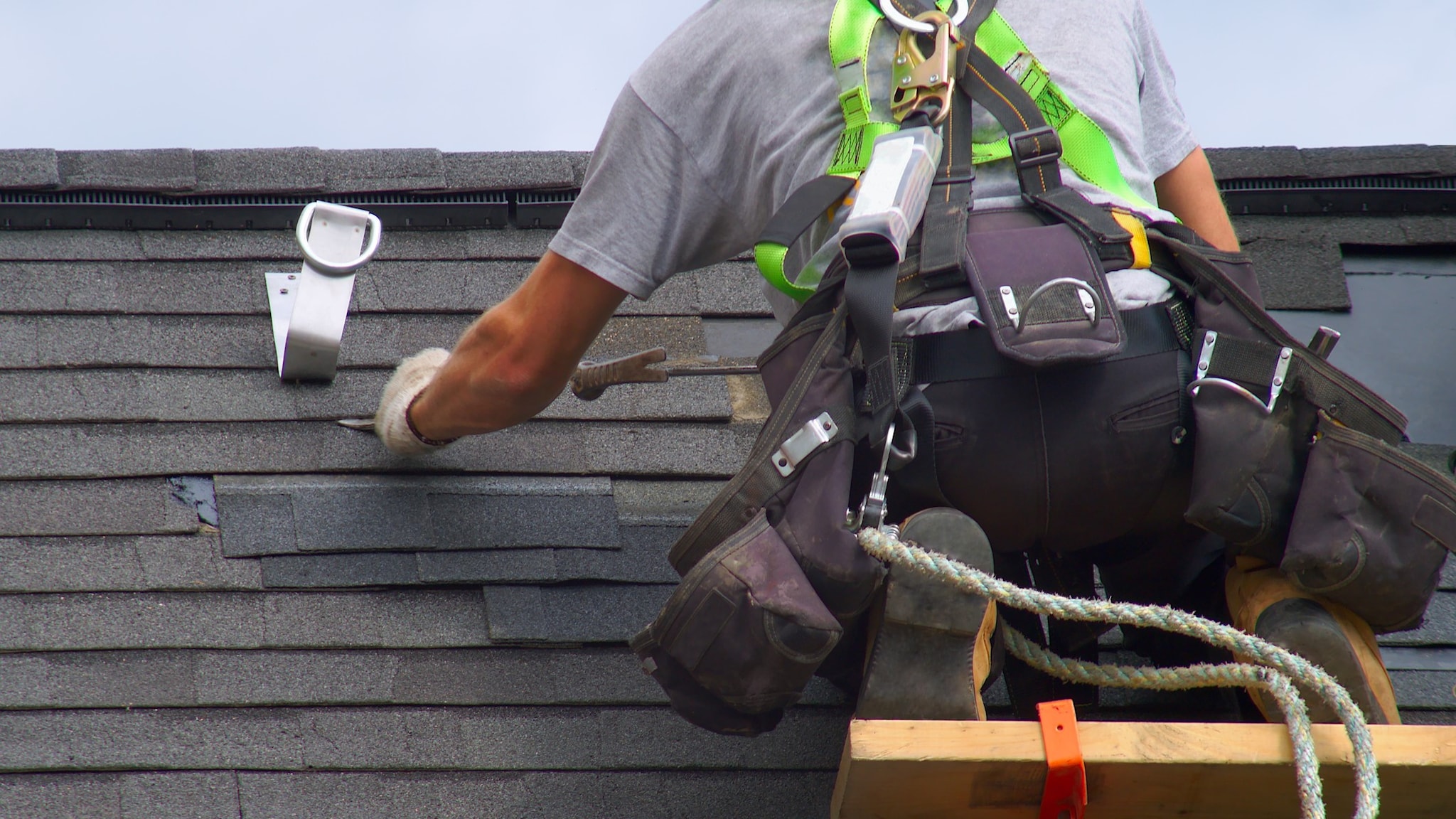 A man is on a roof working on shingles. Photo credit Getty images/jacquesdurocher.