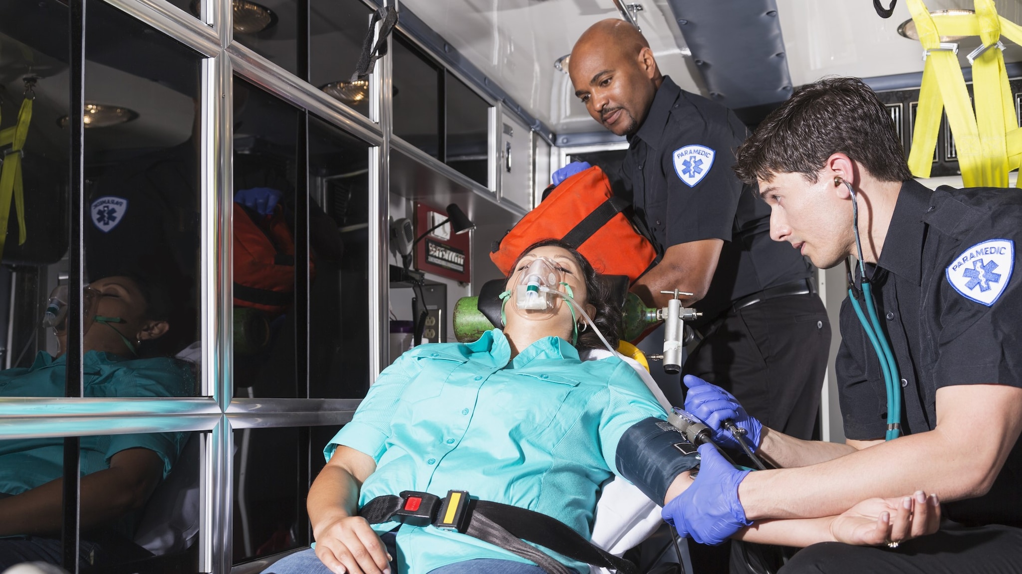 Two EMS clinicians help a patient in an ambulance. Photo by Getty/482584125