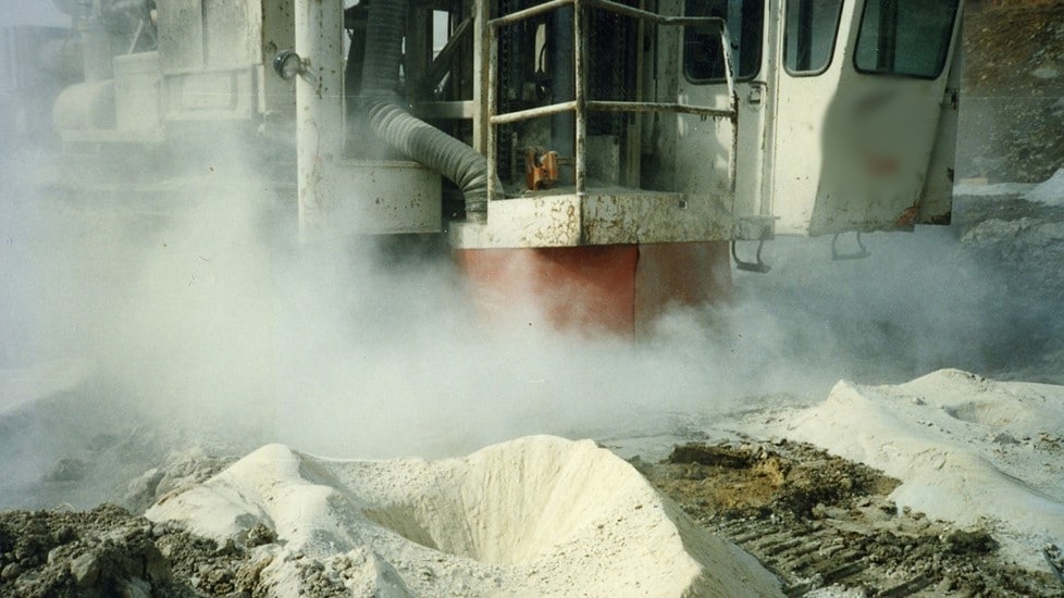 A dusty surface mining drill operation where dust control is not being implemented.