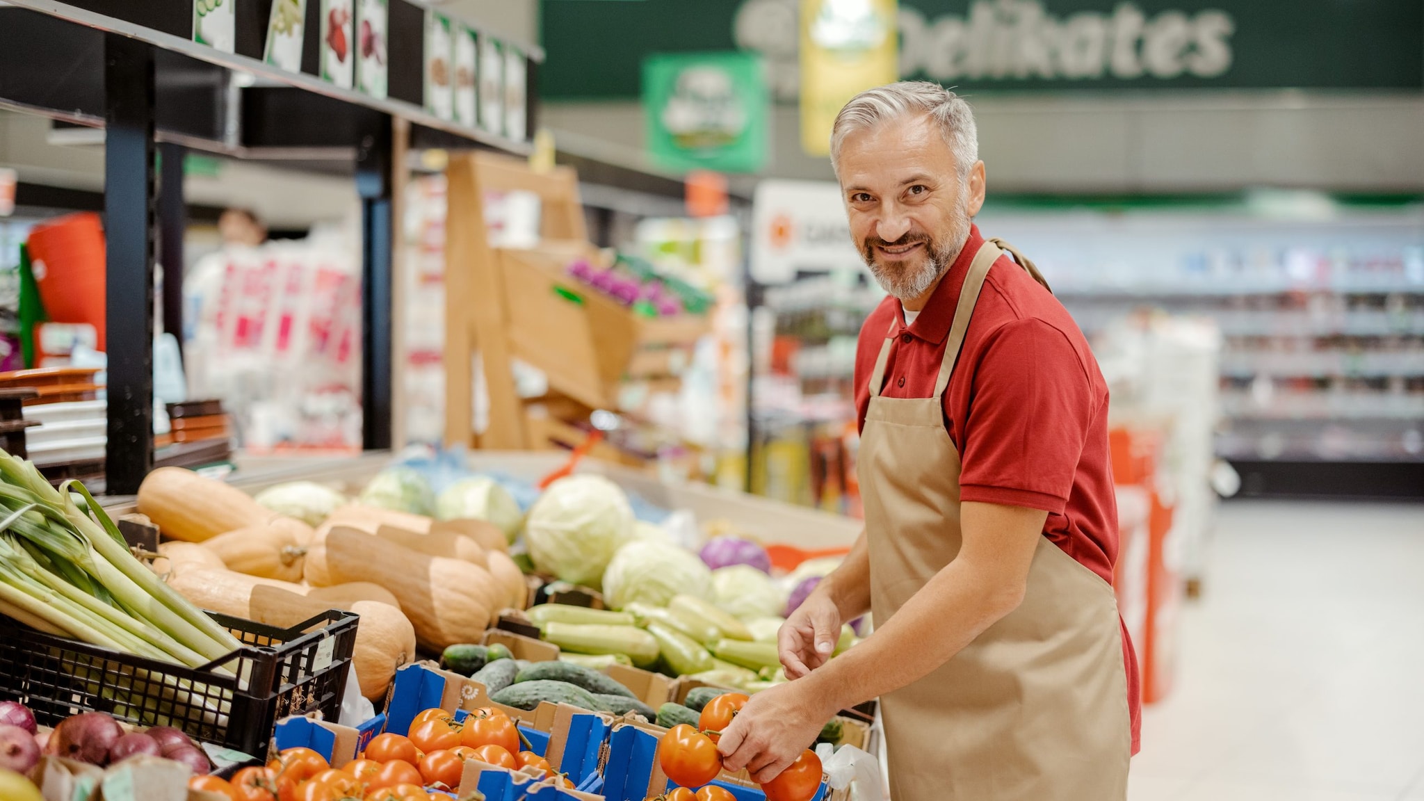 Male grocery store attendant near produce section