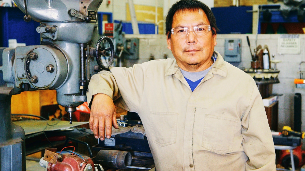 An Indigenous Navajo business owner, standing in a garage workshop.