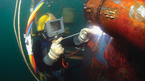 Diver welds a repair patch on the submerged bow of the USS Ogden (LPD 5) while the ship was in port at Naval Base San Diego, California. Image credit: iStock / Getty Images Plus