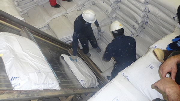Seafood Processors offload bags of fish meal from a ship's hull. Image credit: American Seafoods Group