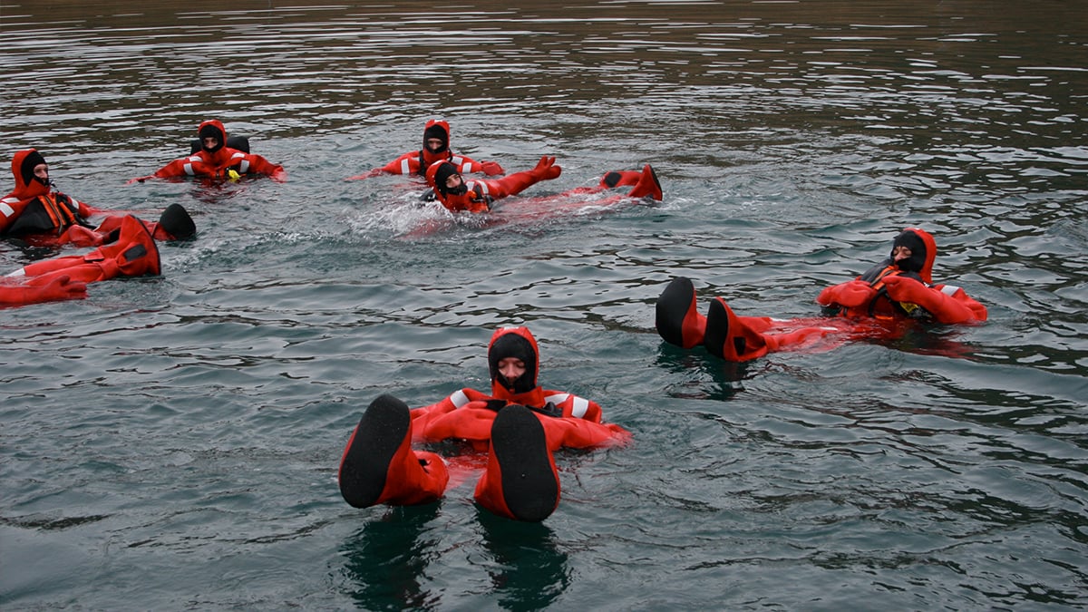 Commercial fishermen participate in an abandon ship/immersion suit donning training event.