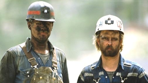 Two coal miners with coal dust on them.