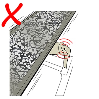 Illustration of ore on a moving conveyor belt and with the conveyor belt roller making noise and requiring lubrication, with a red X in the corner of the image used to represent this maintenance need as a poor practice in relation to protecting worker hearing.