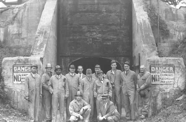 Old photo of miners standing before a mine portal
