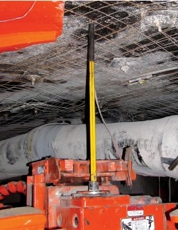 Photograph of a roof bolting machine positioned against the mine roof with the drill bit isolator between the drill steel and drill bit.