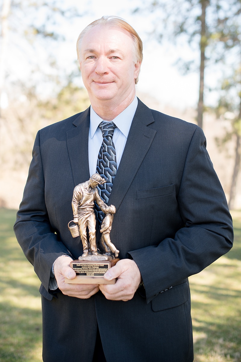 A photograph of Jack D. Trackemas standing and holding the SME Health and Safety Individual Excellence Award.