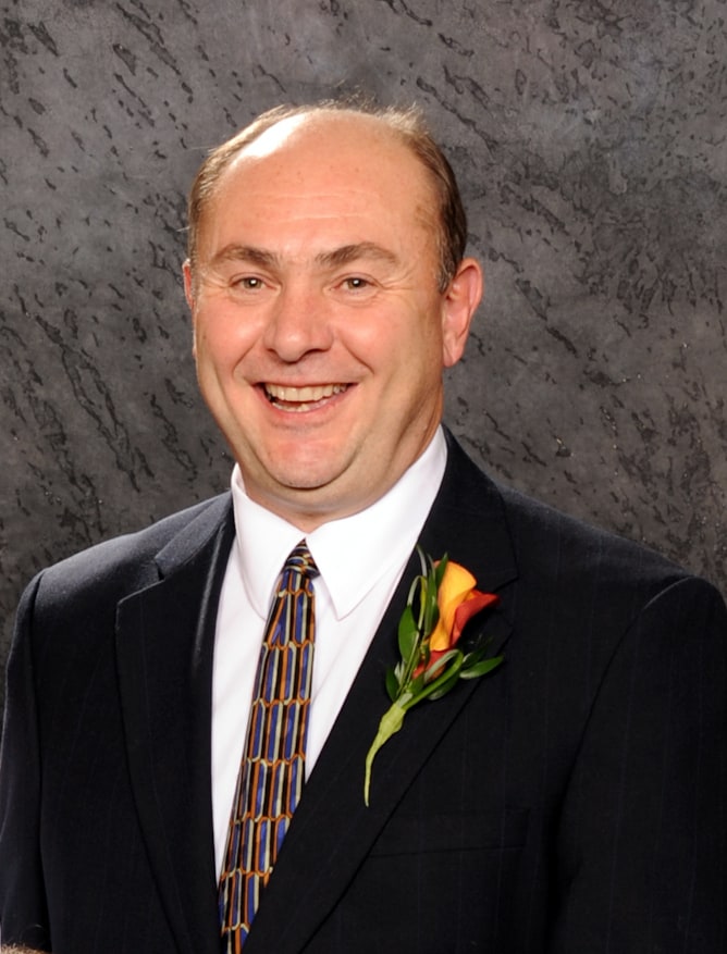 Image of man in suit smiling with lapel flower