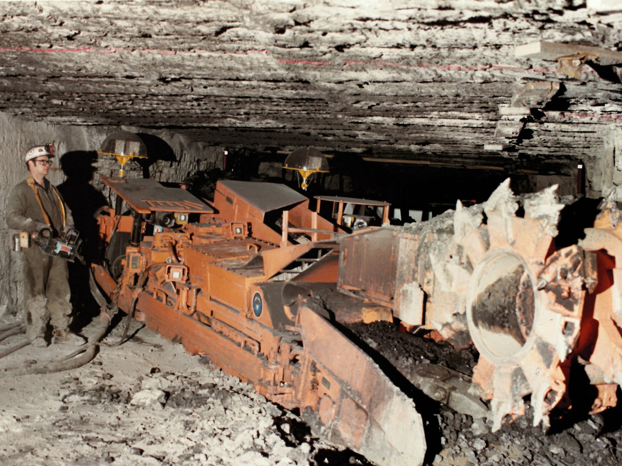 A researcher stands near the Joy 14CM continuous mining machine in an underground mine. 