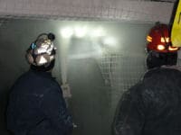 2 miners rock dusting a mine entry.