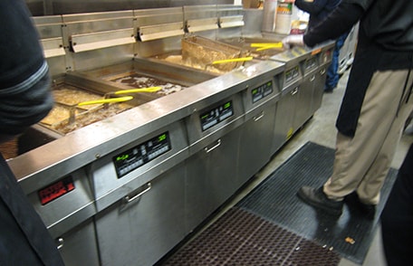 Food services workers working near kitchen fryers and exposed to grease on the floor.