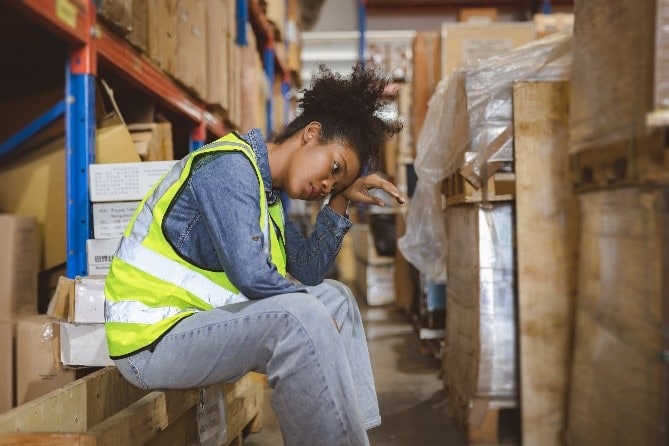 Woman working in a warehouse sitting to take a break.