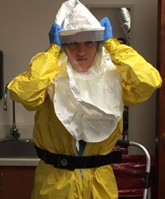 Nurse demonstrating the donning of PPE worn by healthcare providers when treating an Ebola patient in a medical intensive care unit (ICU)