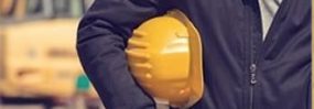 This image shows someone holding a yellow hard hat under their arm