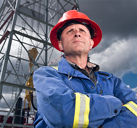 Oil worker standing in front of an oil rig. Photo by ©shotbydave/Getty Images