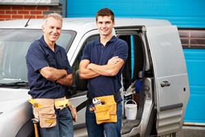 Two construction workers standing outside of a truck