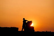 Silhouette of man loading hay bales