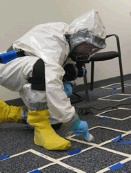 NIOSH investigator practices collecting Bacillus anthracis spores in Level C personal protective equipment during an anthrax exercise.