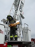 A firefighter is climbing an aerial ladder while in gear. 