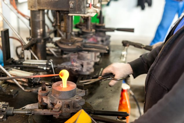 Worker making glass bottle in factory-type setting
