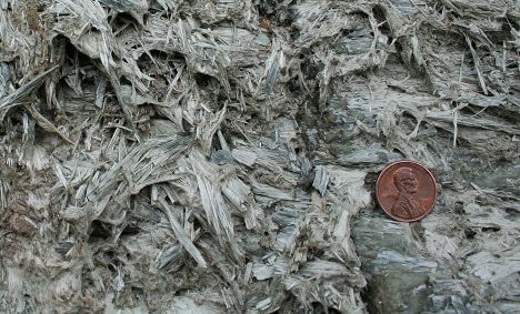 Asbestos with a penny to show the size