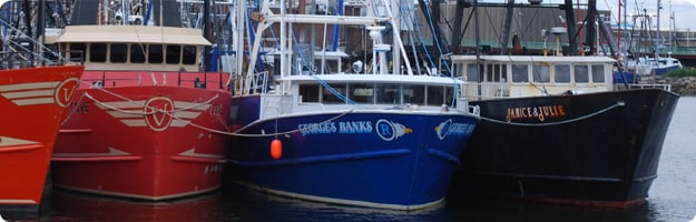 A close up photo of three New Bedford commercial fishing boats tied up at the dock. Photo by NIOSH.