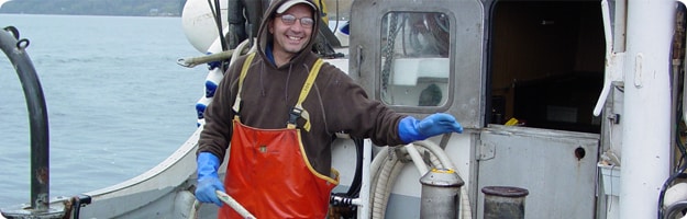 A fisherman simulates the activation of the winch-mounted emergency stop system on the deck of the salmon purse seiner.