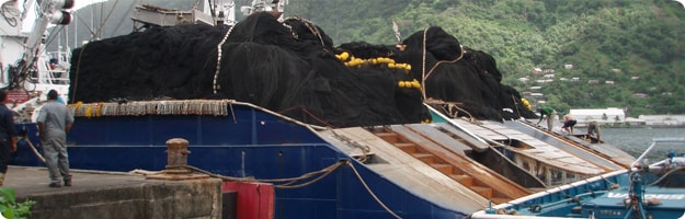 An image of the rear deck of a tuna purse net vessel with nets stacked preparing to leave the dock.