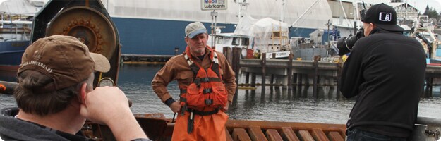 An image of a photo shoot for the Live to be Salty project being conducted on the deck of a crab vessel in Seattle, WA