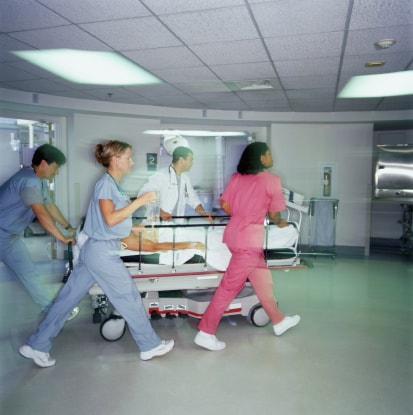 Healthcare workers rushing patient in hospital bed in a hospital.