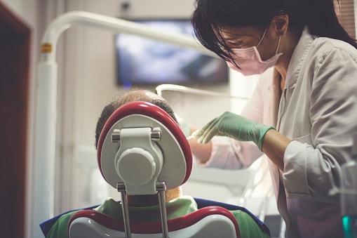Image of dental assistant wearing a mask who is working on a patient who is hooked up to nitrous oxide.