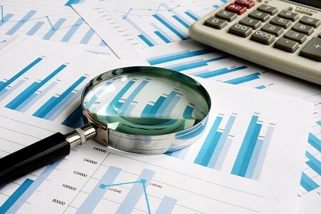 Business papers with financial report and magnifying glass