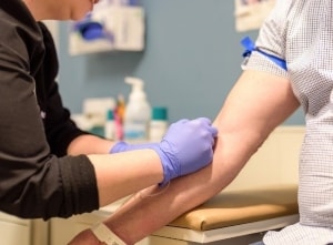 Medical professional drawing blood from patient’s arm 